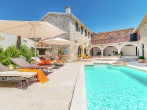 a pool with chairs and umbrellas next to a building at Rustic villa in Vrsar with private swimming pool in Marasi