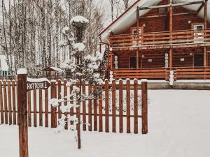 una cerca en la nieve frente a una cabaña de madera en Park Hotel Volzhsky Priboy, en Kostroma