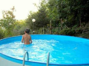 Ein kleiner Junge sitzt im Pool. in der Unterkunft Belvilla by OYO Cozy Holiday Home with Pool in Carbuta