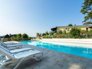 a swimming pool with two lounge chairs next to it at Modern Apartment in Lombardy with swimming pool and garden in Montinelle