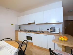 a kitchen with white cabinets and a table with a microwave at Belvilla by OYO Fiamme in Predazzo