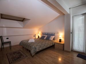 a bedroom with a bed and a chair and a window at Belvilla by OYO Fiamme in Predazzo
