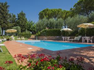una piscina con tavoli e ombrelloni in giardino di Belvilla by OYO PiniOlmo a Bagnolo