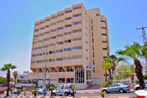 un gran edificio con coches estacionados frente a él en Aquamarine Hotel en Eilat