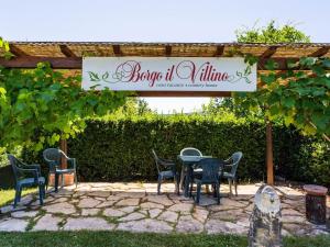 una mesa y sillas bajo una pérgola con un cartel en Tuscan Countryside Stay, en Casole dʼElsa