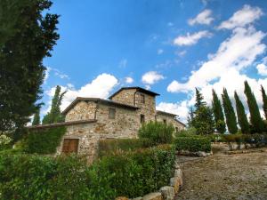 une ancienne maison en pierre avec des arbres et un ciel bleu dans l'établissement Belvilla by OYO Uva, à Radda in Chianti