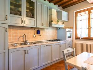 cocina con armarios blancos, fregadero y mesa en Charm farmhouse with pool, en Castiglion Fiorentino