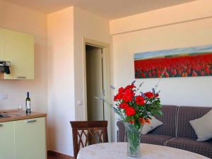 a vase of red flowers on a table in a living room at Flat with swimming pool garden BBQ and parking in Arcevia