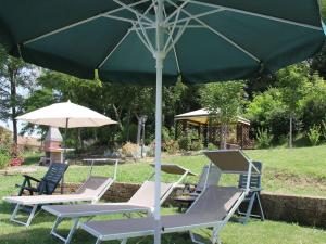 a group of lawn chairs and an umbrella at Flat with swimming pool garden BBQ and parking in Arcevia