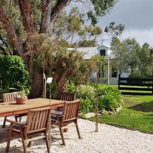 a wooden table and chairs in a garden at Clonmara Country House and Cottages in Port Fairy