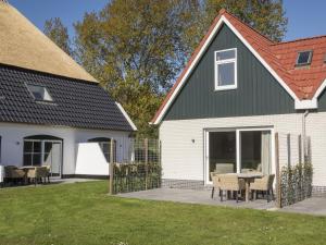 a white house with a black roof and a patio at Bungalow on Texel with a spacious terrace in De Cocksdorp