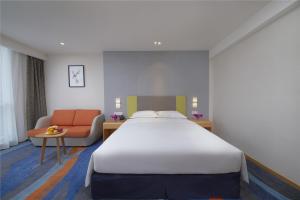 um quarto de hotel com uma cama grande e um sofá em Holiday Inn Express Zhengzhou Zhengdong, an IHG Hotel em Zhengzhou