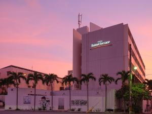 a large building with palm trees in front of it at Hotel Sunset Terrace in Chatan