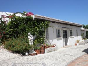 une maison blanche avec des fleurs et des plantes devant elle dans l'établissement Gorgeous Holiday Home with Swimming Pool, à Odiáxere