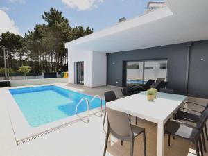 a villa with a swimming pool and a table and chairs at Modern villa with private pool near the beautiful beach of Foz de Arelho in Nadadouro