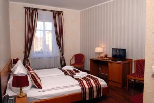 a hotel room with a bed and a desk and a window at Hotel Schwarzer Bär in Zittau