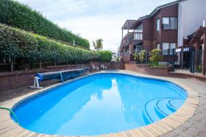 a large blue swimming pool in front of a house at Cascades Lakefront Motel in Taupo