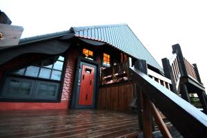 a house with a red door and a wooden deck at Fanlin House in Jialin