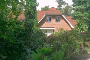 une maison vue à travers les arbres et les buissons dans l'établissement Ferienwohnung Kiefernblick-Wedemann, à Bispingen