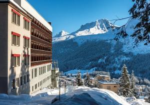 a building with snow on the ground next to a mountain at Arosa Mountain Lodge in Arosa