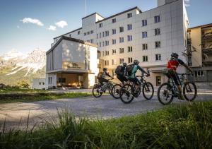 three people riding bikes in front of a building at Arosa Mountain Lodge in Arosa
