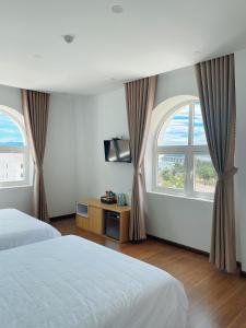 a bedroom with two beds and two windows at THE VILLA HIEU HY in Quy Nhon