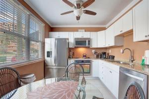 a kitchen with white cabinets and a ceiling fan at Clearwater Beach Suites 102 condo in Clearwater Beach