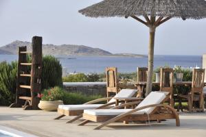 a group of chairs and an umbrella and a table at Anemoi Resort in Naousa