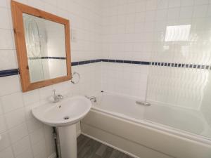 a bathroom with a sink and a tub and a mirror at Sandy Cove in Chathill +21 photos