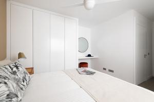 a white bedroom with a bed and a mirror at Royal Flats in Las Palmas de Gran Canaria