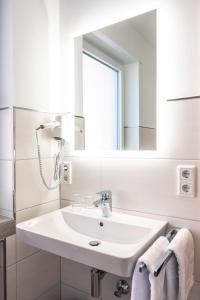 a white bathroom with a sink and a mirror at Landgasthof-Hotel Zum Steverstrand in Lüdinghausen