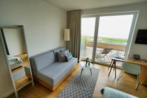 a living room with a blue couch and a balcony at Hotel Strandhus in Cuxhaven