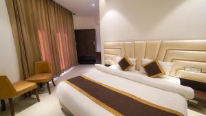 アムリトサルにあるHOTEL AVI INN BY JR GROUP OF Hotels 50 Meter from Golden Templeの大きなベッドと椅子が備わるホテルルームです。