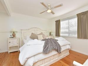 ein weißes Schlafzimmer mit einem Bett und einem Deckenventilator in der Unterkunft Olive Grove 3 1 Bedroom Villa with large Bath in Pokolbin