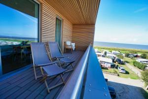 einen Balkon mit blauen Stühlen, einem Tisch und Meerblick in der Unterkunft Hotel Strandhus in Cuxhaven