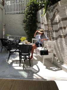 a woman sitting on a bench on a patio at Faces Art Suites in Rhodes Town