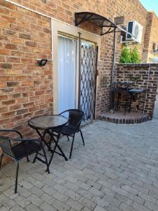a patio with a table and chairs and a brick wall at Skietberg Lodge in Colesberg