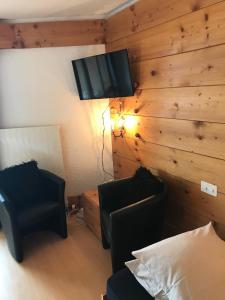 ein Wohnzimmer mit 2 Stühlen und einem TV an der Wand in der Unterkunft Appartement - Bristol Hôtel in Villars-sur-Ollon