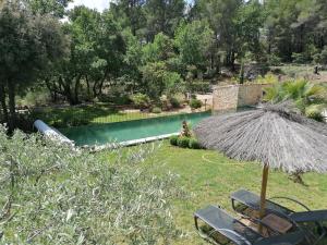 una piscina con 2 sillas y una sombrilla en La Petite perle, balnéo en supplément, le Clos des Perles, en Tourtour