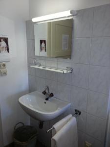 ein weißes Badezimmer mit einem Waschbecken und einem Spiegel in der Unterkunft Gasthof Simony Hallstatt B&B in Hallstatt