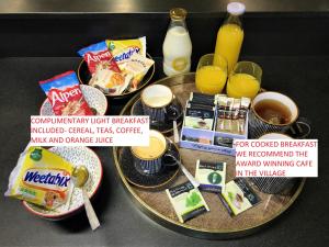 einen Tisch mit einem Tablett mit Frühstücksspeisen und Getränken in der Unterkunft Hillside Farm Barn in Woking