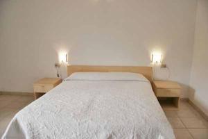a bedroom with a white bed with two nightstands and two lamps at Agriturismo Sa Mandria in Castiadas
