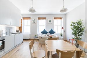 Stylish Stays by Russel Square في لندن: مطبخ وغرفة معيشة مع طاولة وكراسي