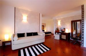 a living room with a white couch and a bedroom at Cala Rosa Club Hotel in Stintino