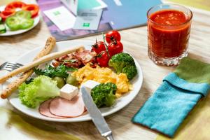 uma mesa com um prato de alimentos com brócolos e legumes em Ibis Styles Lviv Center em Lviv