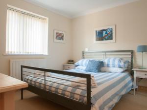 a bedroom with a bed with blue and white sheets at 1 Crabshell Quay in Kingsbridge