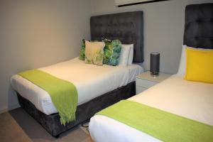 a bedroom with two beds with green and yellow pillows at Zimbali Suites 324, Capital Hotel Complex in Ballito