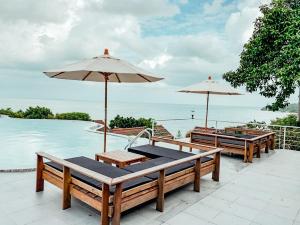a patio with tables and umbrellas next to the water at High Life Bungalow in Haad Yao