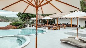 a swimming pool with an umbrella and tables and chairs at High Life Bungalow in Haad Yao