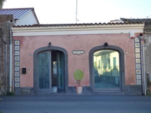 un bâtiment avec deux portes et une usine de pot devant dans l'établissement Oltre Il Giardino, à Pedara